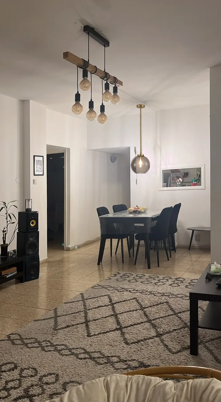 אחרי: מנורת תלייה מזכוכית עשנה מעל שולחן האוכל. מנורת הקורה מעל הסלון נשארה במקומה